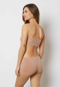 Nude sömlös bandeau-topp i kombination med matchande korta underkläder. Mjuk, elastisk tyg med en jämn yta och minimalistisk design.