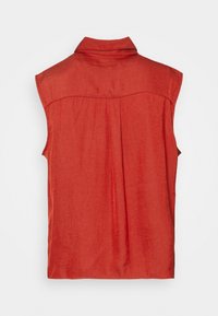Maglietta rossa senza maniche con colletto, texture morbida e pieghe posteriori. Design semplice, realizzata in tessuto leggero.