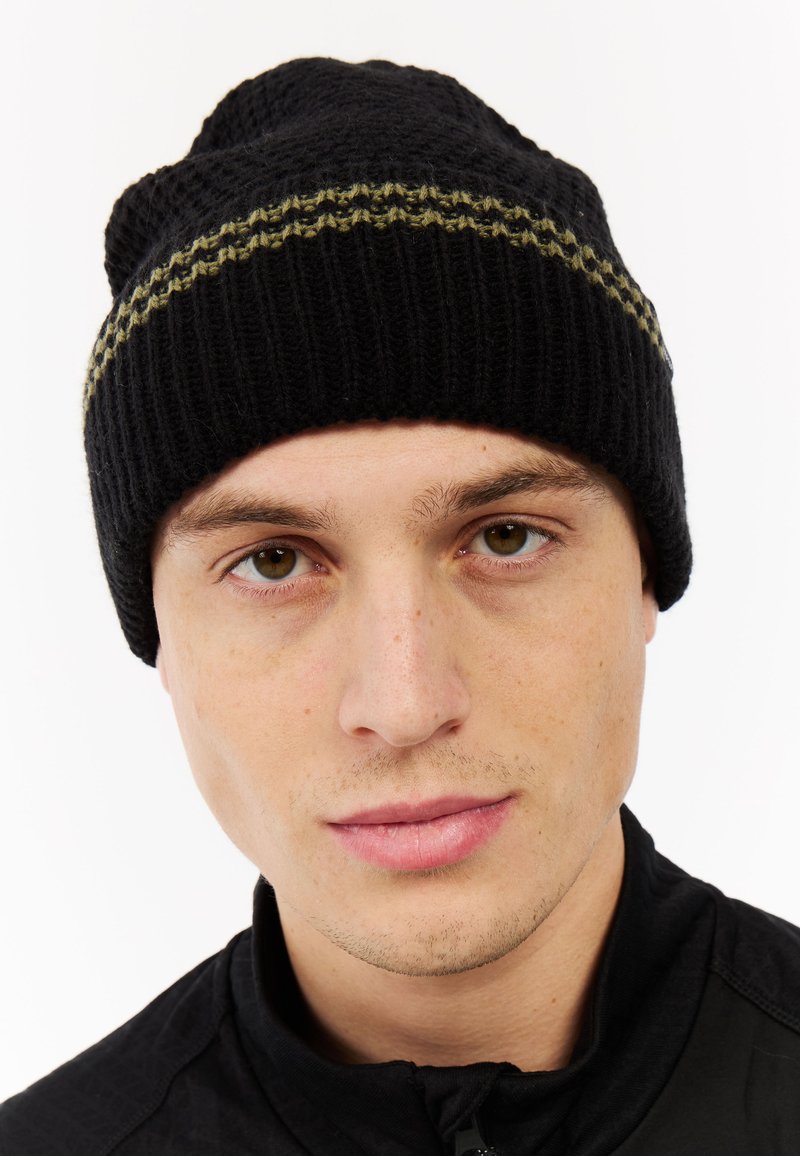 Zwarte gebreide muts met een gestructureerd patroon. Heeft een gouden streep rond de rand. Zacht materiaal, aansluitend ontwerp.