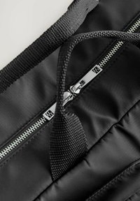 Borsa imbottita nera con cerniera centrale argento, manici rinforzati e tessuto texturizzato con cuciture nere a contrasto.