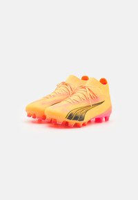 Scarpe da calcio giallo brillanti con tomaia testurizzata, dettagli neri e suola a gradiente rosa. Progettate per una presa e prestazioni ottimali.