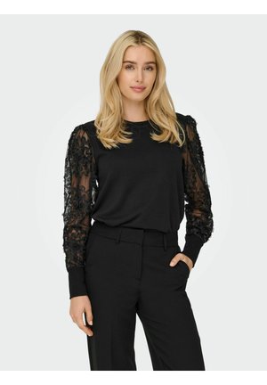 Top noir avec des manches en dentelle florale, col rond et poignets ajustés, assorti à un pantalon noir. Tissu lisse avec des accents texturés sur les manches.