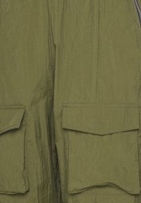 Olivgröna cargobyxor med en texturerad yta, som har två framfickor och kontrasterande sömdetaljer.