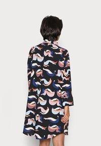 Schwarzes Kurzarmkleid mit einem bunten abstrakten Muster aus geschwungenen Formen in Pink, Blau und Weiß, betont durch einen Kragen und einer lässigen Passform.