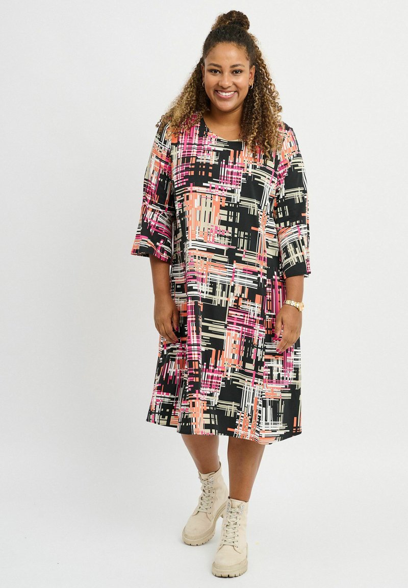 Vestido multicolorido con fondo negro, presenta un patrón abstracto en rosa, blanco y beige. Hasta la rodilla con mangas de tres cuartos.