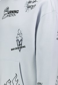 Hellgraues Hoodie mit schwarzen Drucken, die Flammen, ein Herz und Sprüche zeigen. Es hat eine Kängurutasche und gerippte Bündchen.