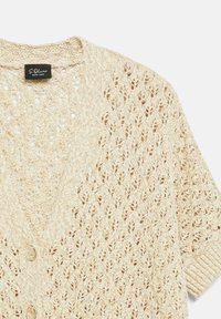 Beige knitted cardigan with openwork pattern, ribbed sleeve cuffs, and two gold decorative buttons on the front.