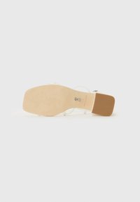 Beige højhælede sandaler med firkantet tå og kraftig hæl, udstyret med ankelrem samt en glat, struktureret læderoverdel.