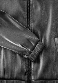 Czarna satynowa kurtka bomberka z zamkiem błyskawicznym z przodu, ściągaczami na rękawach oraz gładką fakturą o subtelnym połysku.