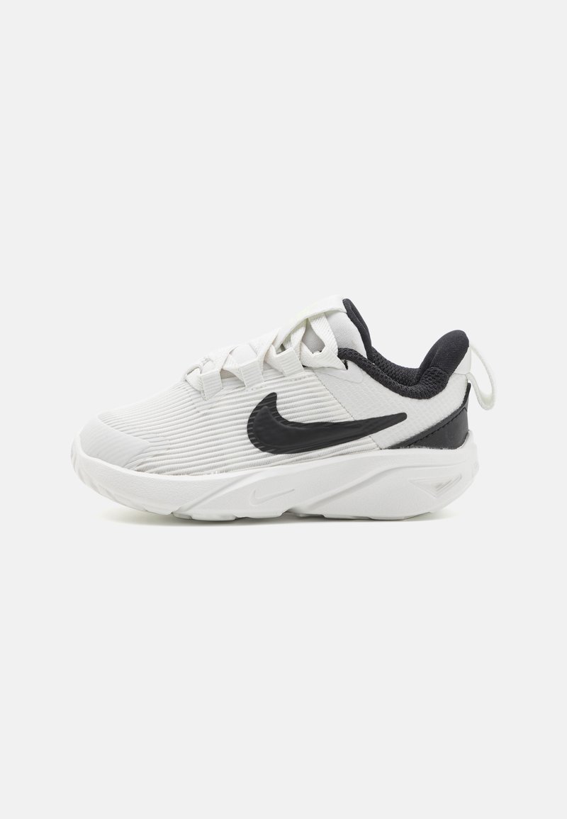 Baskets Nike blanches et noires avec un tissu texturé, logo Swoosh noir, lacets blancs et semelle épaisse et rembourrée, vues de côté sur un fond blanc.