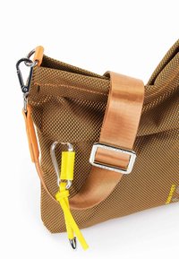 Borsa in tessuto marrone con una robusta tracolla gialla, parti in metallo e un accento arancione a contrasto sulla chiusura e sull'aggiustamento della tracolla.