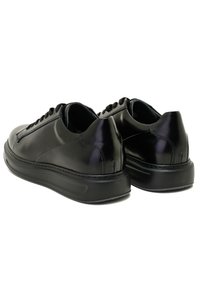 Schwarze Leder-Sneaker mit einem schlanken, glatten Finish, runder Zehenpartie, gepolsterter Sohle und schwarzen Schnürsenkeln, verziert mit Steppnähten an den Seiten.