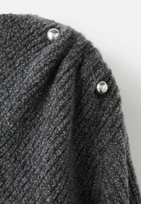 Tejido de punto gris oscuro con un acabado texturizado, que presenta tres broches metálicos brillantes a lo largo del borde para el cierre.