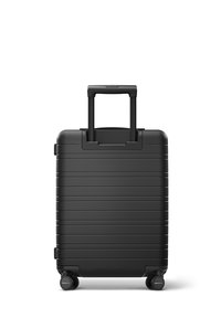 Valise rigide noire de cabine avec des rainures horizontales, une poignée télescopique et quatre roues. Texture lisse et design robuste.