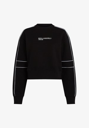 Mustad must cropped-sviiter pikkade varrukatega, ribatud mansettide ja ümmarguse kaelusega. Omab valgeid triibusid varrukatel ja logoteksti rinnal.