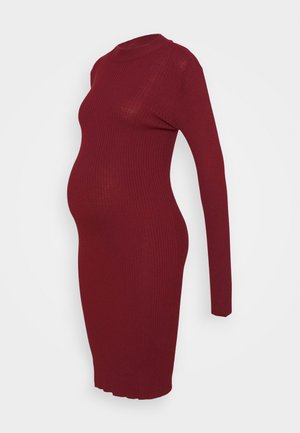 Robe de maternité en maille côtelée bordeaux avec manches longues et col montant, conçue pour s'adapter à un ventre qui grandit.