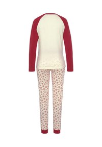 Rood en crèmekleurig long-sleeve shirt met raglanmouwen, gecombineerd met crèmekleurige broek met een rood sneeuwvlokpatroon. Zachte stof, losse pasvorm.