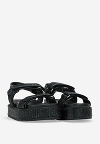 Sandalias de plataforma negras con upper trenzado, doble correa, herrajes en tono dorado y suelas texturizadas. Diseñadas para la comodidad y la durabilidad.