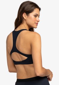 Marineblauwe sport-bh met een racerbackontwerp, voorzien van uitsnijdingen en gladde stof. Verstelbare banden en elastische band aan de onderkant.
