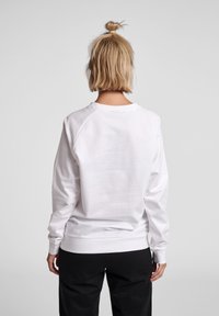 Felpa bianca in cotone con maniche lunghe, polsini a coste e scollatura rotonda. Tessuto morbido, vestibilità casual, con design delle maniche a raglan.
