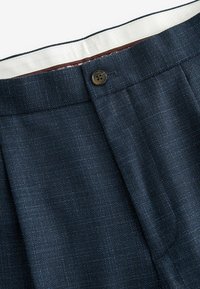 Navy blue tailored trousers with a textured fabric, featuring a single button closure and a contrasting inner waistband.