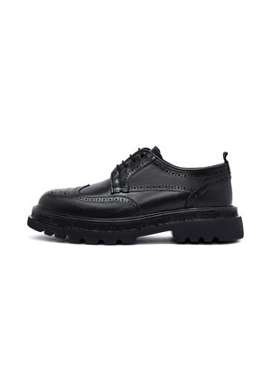 Zwarte leren brogue schoen met vleugeltipdetails, dikke profielzool en vetersluiting, zijaanzicht op witte achtergrond.