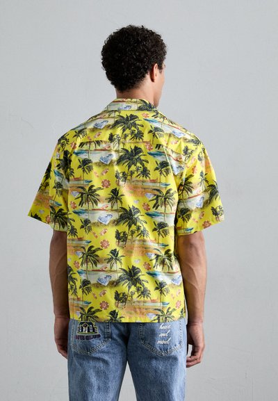 Cămașă cu mânecă scurtă din bumbac galben, cu un imprimeu tropical de palmieri și flori, având culori contrastante și modele detaliate.