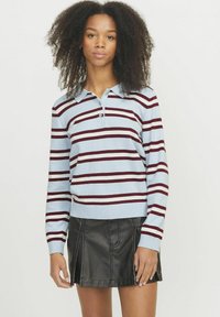 Pullover a righe blu chiaro con righe bordeaux e bianche, dotato di colletto e maniche lunghe, abbinato a una mini gonna in pelle nera.