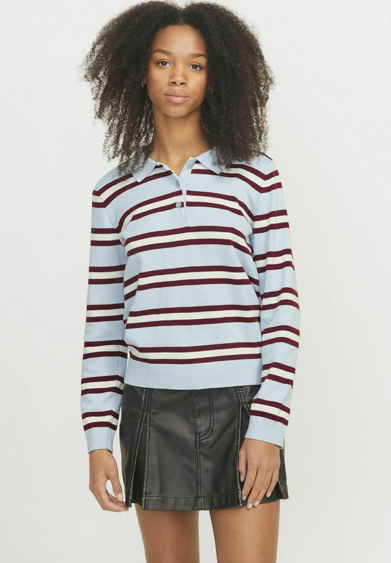 Pullover a righe blu chiaro con righe bordeaux e bianche, dotato di colletto e maniche lunghe, abbinato a una mini gonna in pelle nera.