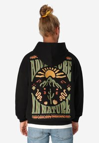 Schwarzer Kapuzenpullover mit einem grafischen Design auf dem Rücken, das Berge, Sonne und dekorative Elemente in Grün, Orange und Gelb zeigt.