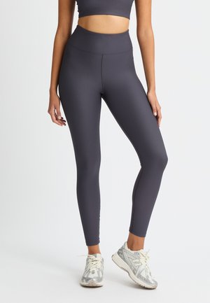 Dark gray ribbed leggings with a high waist, fitted design, smooth texture, paired with light-colored athletic shoes.