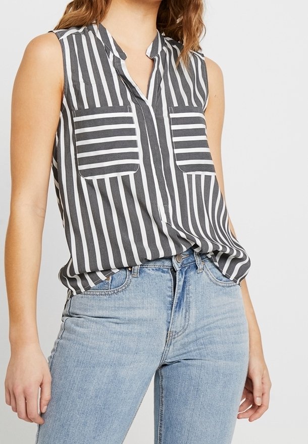 Haut sans manches à rayures gris et blanc, avec un col, deux poches avant et une coupe décontractée, associé à un jean bleu clair.