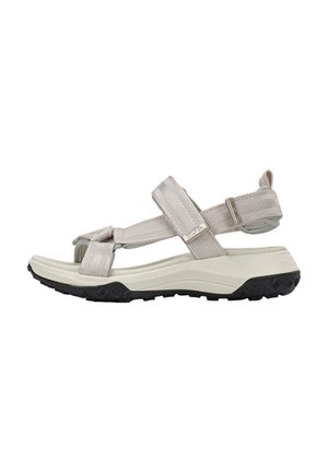 Sandalia deportiva beige con tiras de tela ajustables, suela acolchada y suela exterior de goma texturizada negra, vista lateral.