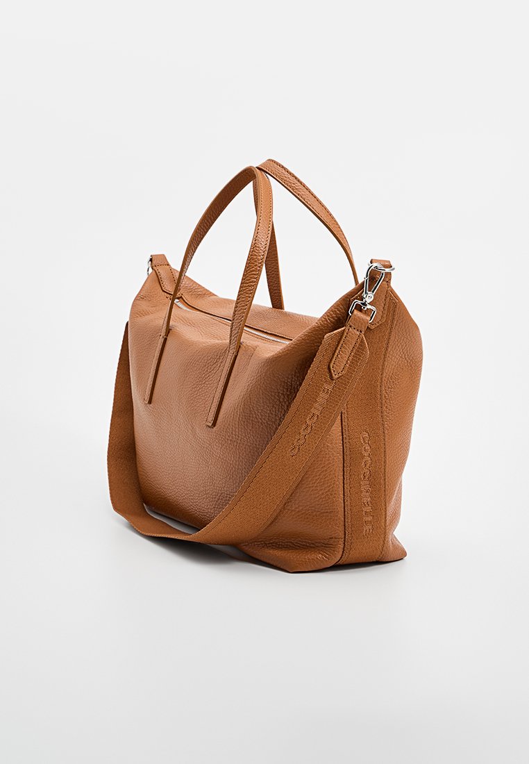 Brązowa skórzana torebka o teksturowanym wykończeniu, z podwójnymi uchwytami u góry i odpinanym paskiem na ramię. Posiada zamek błyskawiczny.