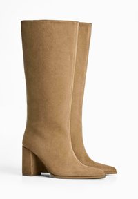 Knähöga stövlar med klack i mjuk taupe mocka, med spetsig tå och slät yta, med rena linjer och minimal dekoration.