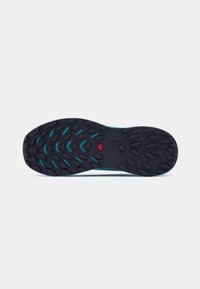 Semelle de chaussure en caoutchouc noir avec motif de grip texturé, comportant des accents turquoise et un détail en forme de triangle rouge au centre.