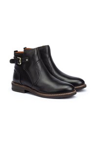 Bottines en cuir noir avec un bout arrondi, des panneaux élastiques sur les côtés et une boucle sur la cheville. Détails de couture et un petit talon.