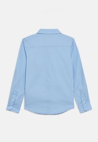 Ανοιχτό μπλε πουκάμισο με μακριά μανίκια και κάθετες λευκές ρίγες, με γιακά που κουμπώνει και μανσέτες με κουμπιά. Λείο ύφασμα και σχεδιασμός με στρογγυλεμένη κάτω άκρη.