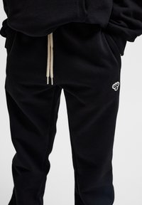 Schwarze Sweatpants aus weichem Material, mit einem entspannten Schnitt, elastischem Bund mit Kordelzug und kleinem, gesticktem Logodetail.