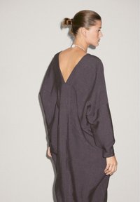 Dunkelgraues Leinenkleid mit V-Ausschnitt und lockeren Ärmeln. Verfügt über ein tiefes Rückendesign und einen weichen, strukturierten Stoff.