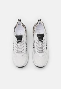 Valkoiset urheilukengät, joissa on teksturoitu pinta, harmaat yksityiskohdat, musta pilkullinen kuvio ja hopeiset nauhat. Koko 37 printattuna sisäpuolelle.