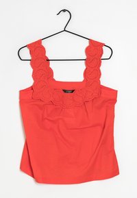 Haut rouge sans manches avec bordure festonnée en broderie anglaise sur les bretelles, texture en coton lisse, devant froncé, et ourlet droit.