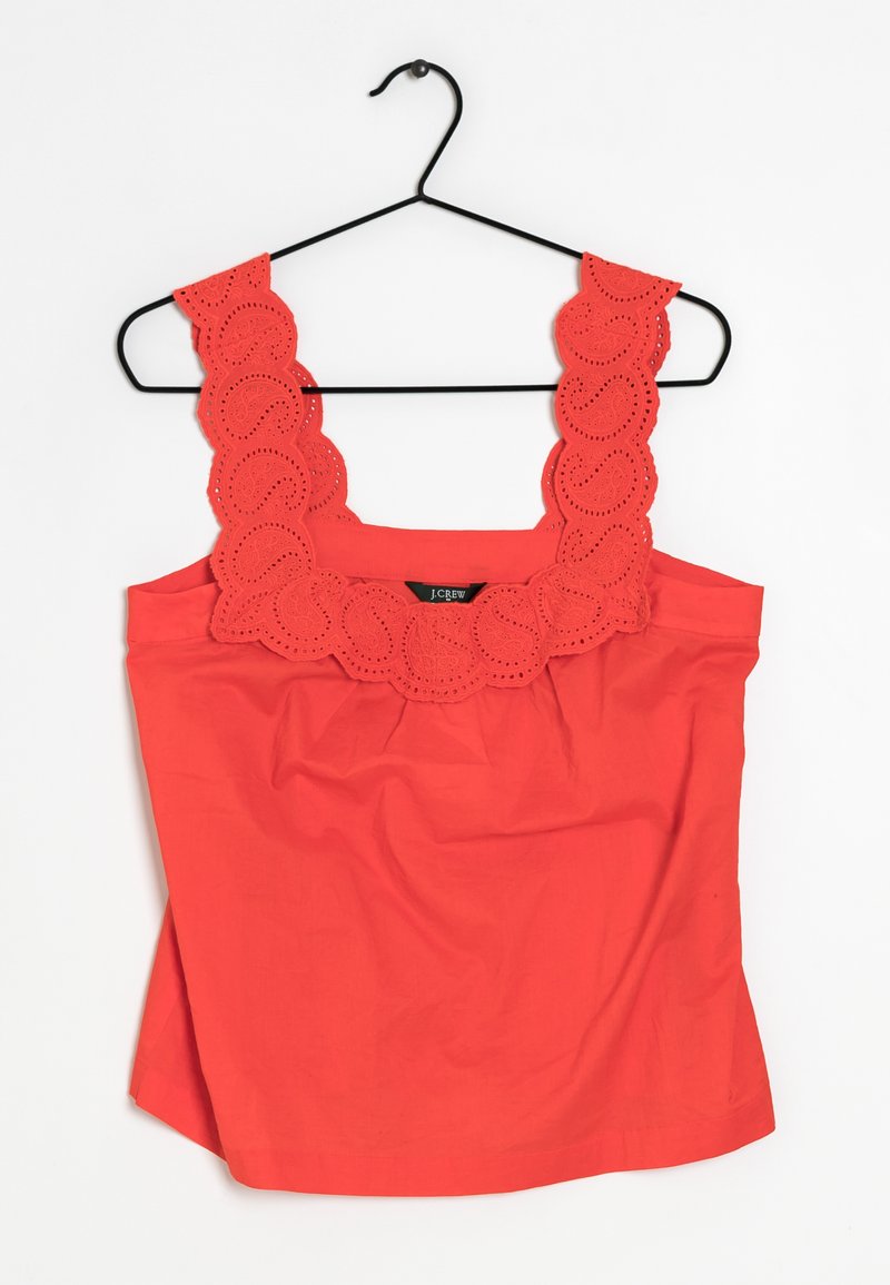 Haut rouge sans manches avec bordure festonnée en broderie anglaise sur les bretelles, texture en coton lisse, devant froncé, et ourlet droit.