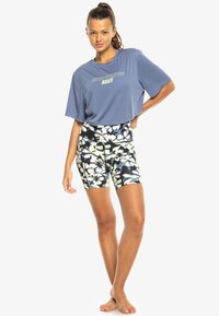 Blue cropped t-shirt with "Roxy" graphic; high-waisted shorts with floral pattern in navy, white, and light blue; smooth fabric texture.