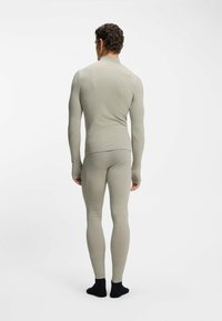 Długi rękaw termicznej bluzki i dopasowane legginsy w jasnoszarym kolorze, prążkowana faktura, z wysokim kołnierzem i bezszwowym wykończeniem. Czarne skarpetki.