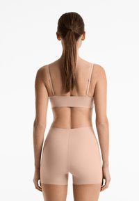 Lichtbeige naadloze bh en shortset, met verstelbare banden en een soepele, rekbare textuur, ontworpen voor comfort en pasvorm.