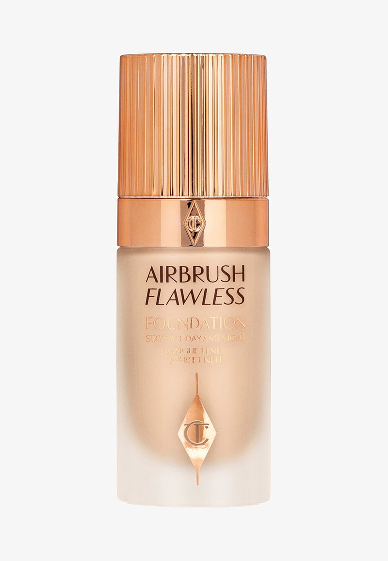 Foundation in einer Glasflasche mit einem goldenen Rippendeckel. Die Basis ist frosted, und das Etikett zeigt "Airbrush Flawless Foundation" in goldener Schrift.
