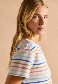 Striped short-sleeve top in cream, featuring blue, pink, and brown horizontal stripes; knit material; soft texture; crew neckline.