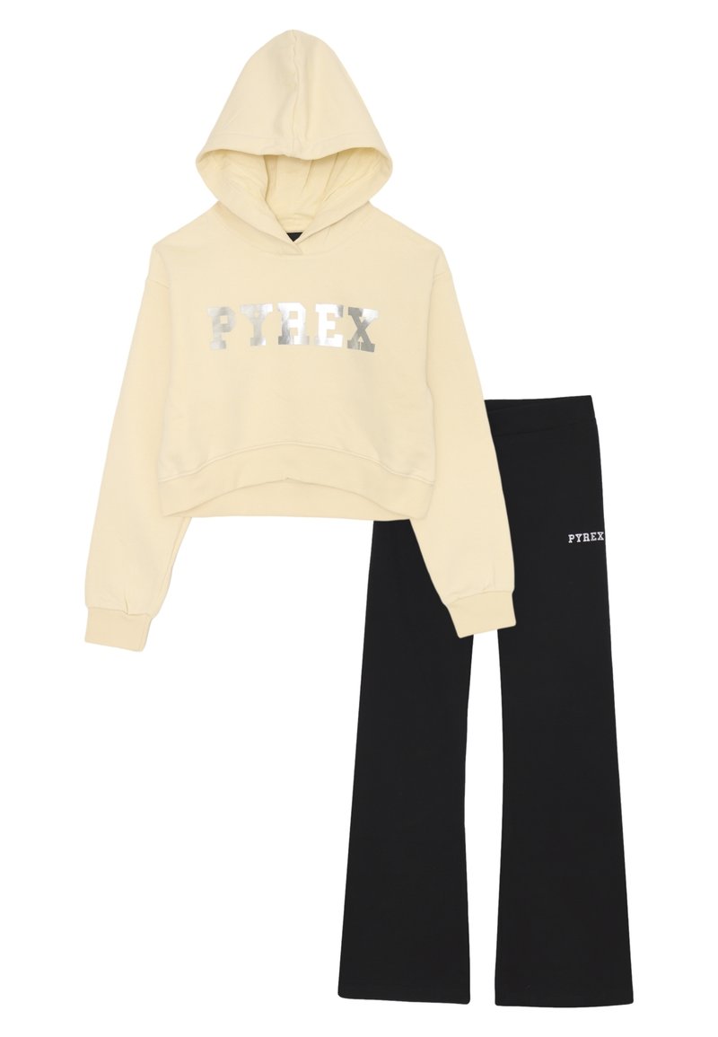 Hoodie cropped beige con testo "PYREX" argento abbinato a pantaloni della tuta neri a campana con piccolo logo bianco "PYREX" sull'anca.