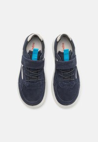 Navy blue sneakers with suede and mesh upper, featuring a velcro strap, laces, and a light-colored rubber sole. Bright blue accent on the strap.